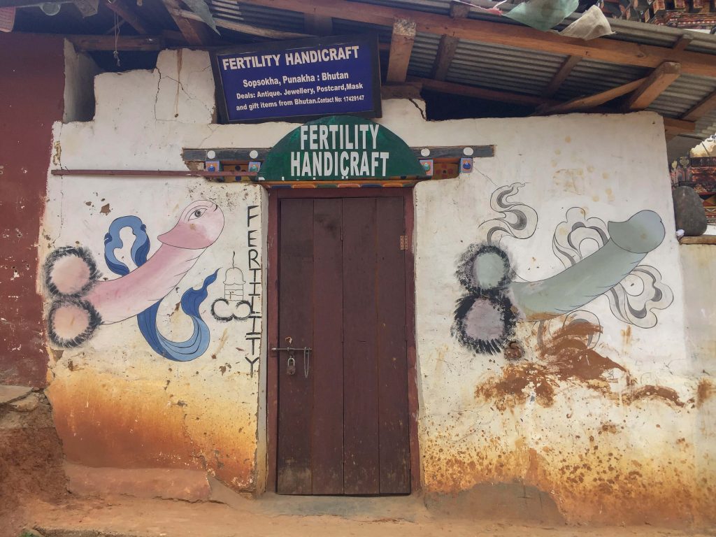 Sacred phallic art of Bhutan decorating the outer walls of a shop advertising fertility handicraft.