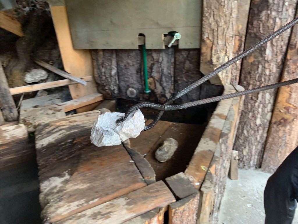 Red hot rocks are dropped one by one into the cornered off section on the tub of a Bhutanese Hot Stone Bath.