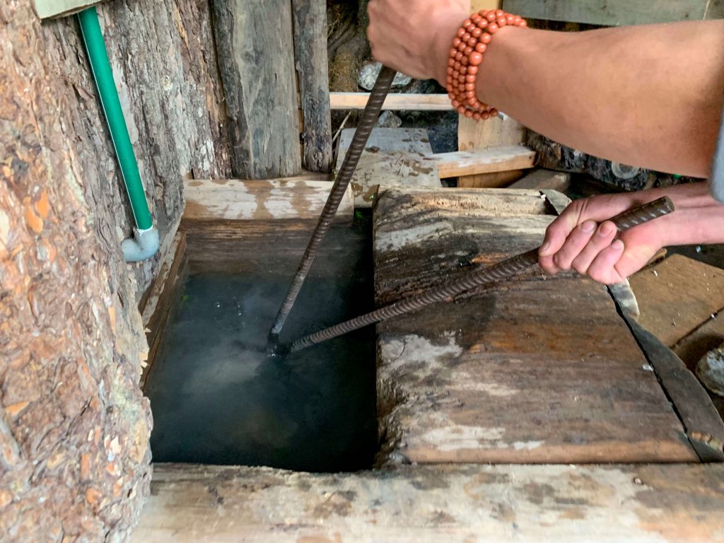 Red hot rocks are dropped one by one into the cornered off section on the tub of a Bhutanese Hot Stone Bath.