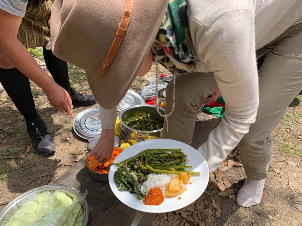 Picnic by the Paro river in Bhutan. Students on the Bhutan Yoga adventure fill their plates with colourful vegetables, rice and sauces.