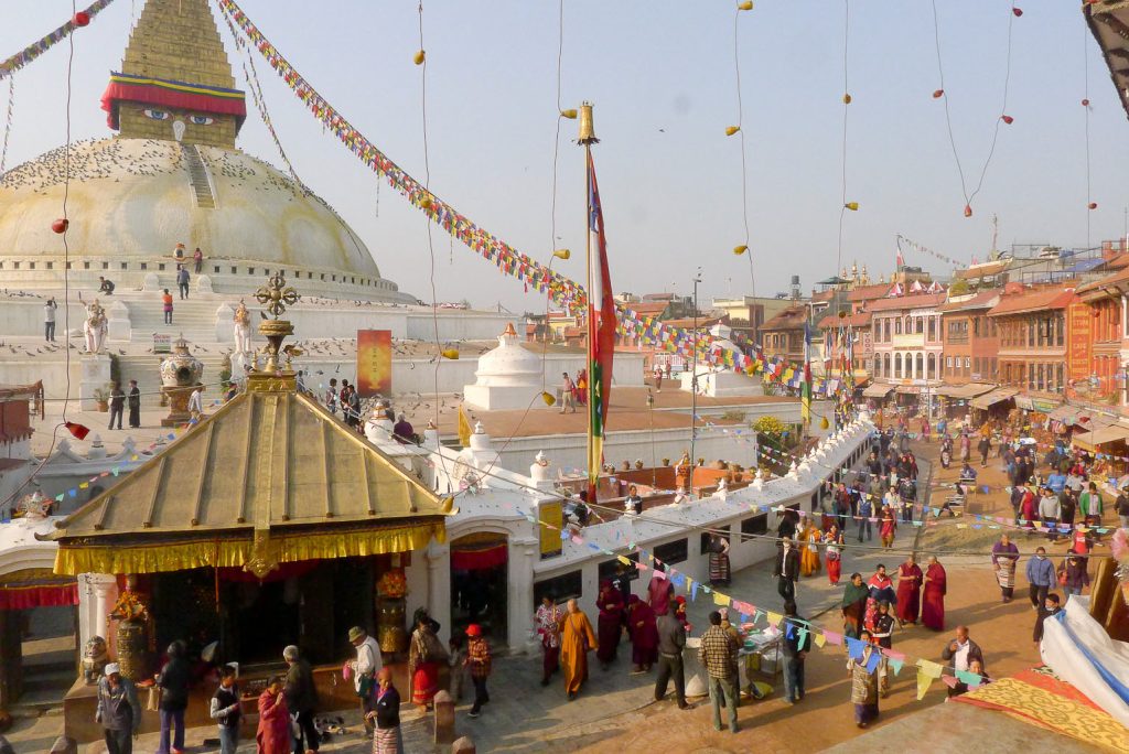 The rising sun shines down on locals and visitors as they walk the kora at Boudhanath Stupa in Boudhanath, Nepal.